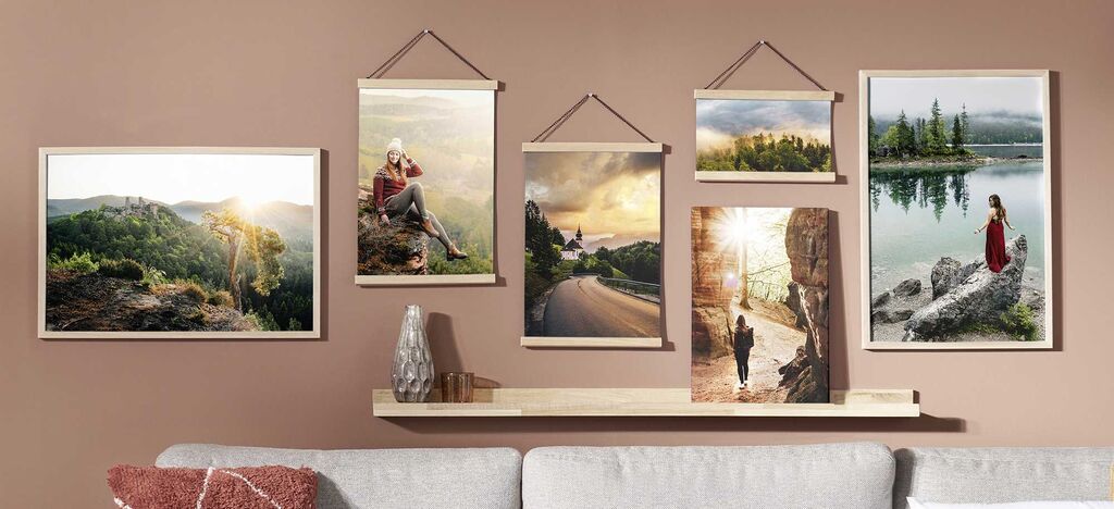 Eine ansprechend gestaltete Wand mit rahmenlosen Bildern von Landschaften und Portraits, die eine warme Atmosphäre erzeugt