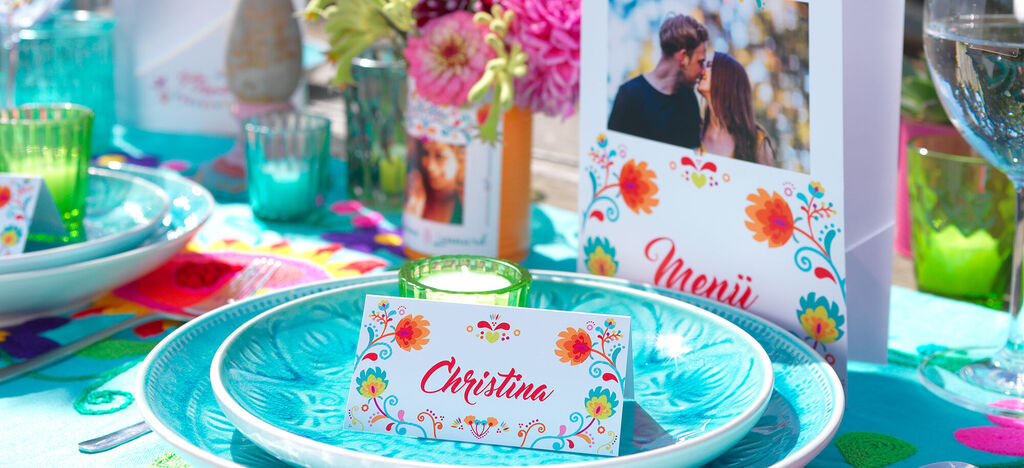 Schöne festliche Tischdekoration mit buntem Geschirr, Blumen und personalisierten Karten