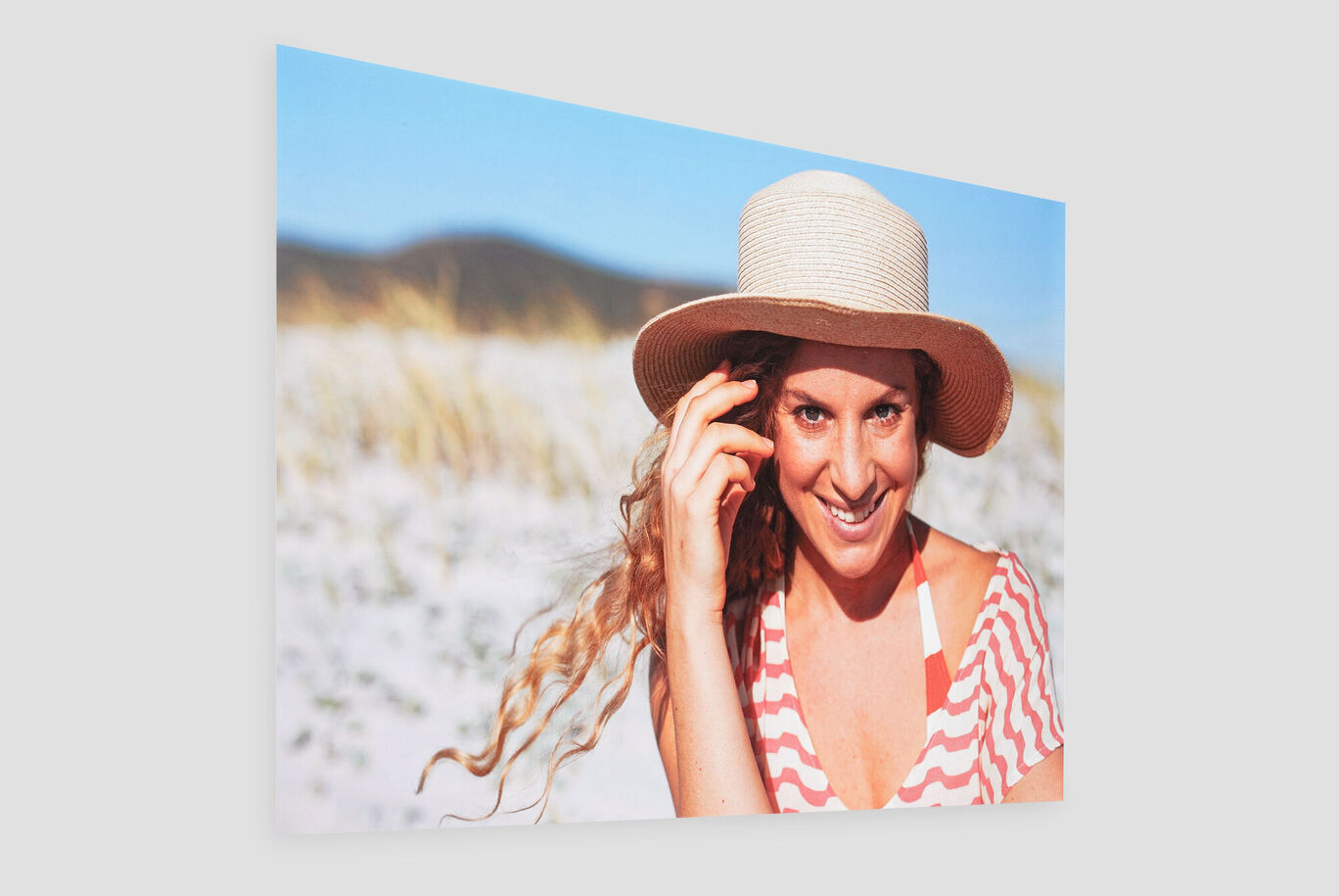 Eine Frau mit Sonnenhut genießt den Strand.