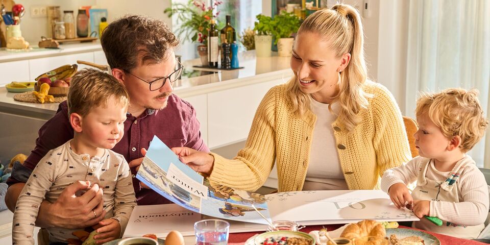 Eine Familie blättert durch ihr individuell gestaltetes CEWE FOTOBUCH Erinnerungen.