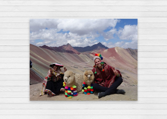 Zwei Personen in traditioneller Kleidung mit zwei Lamas auf einem Berg.