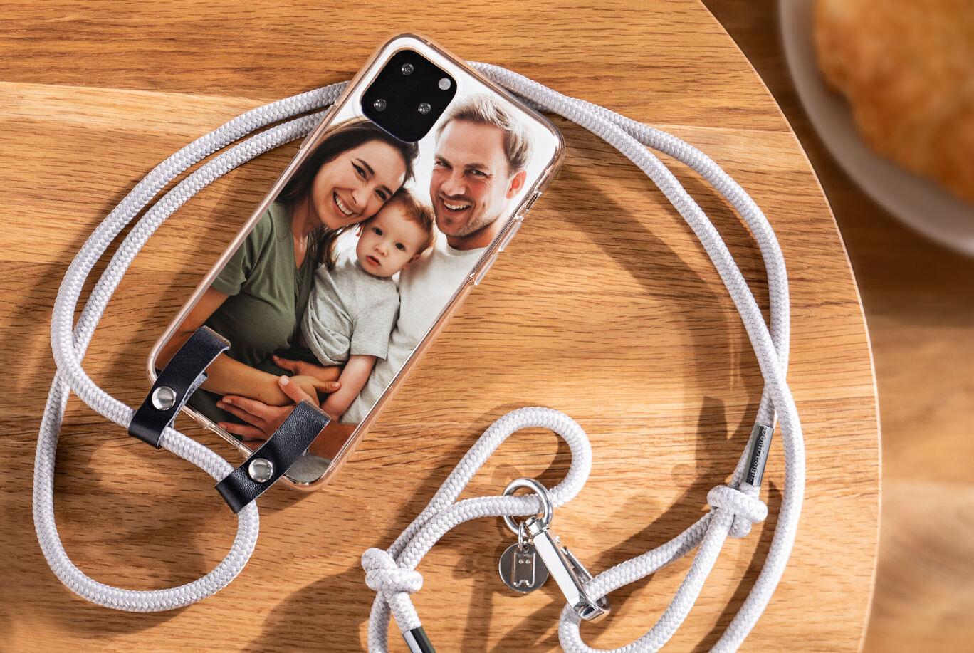 Ein personalisiertes Handyhülle mit einem Familienfoto und einem Schlüsselanhänger auf einem Holzbrett. Perfekt für Ihr Lieblingsmensch um Erinnerungen zu bewahren.