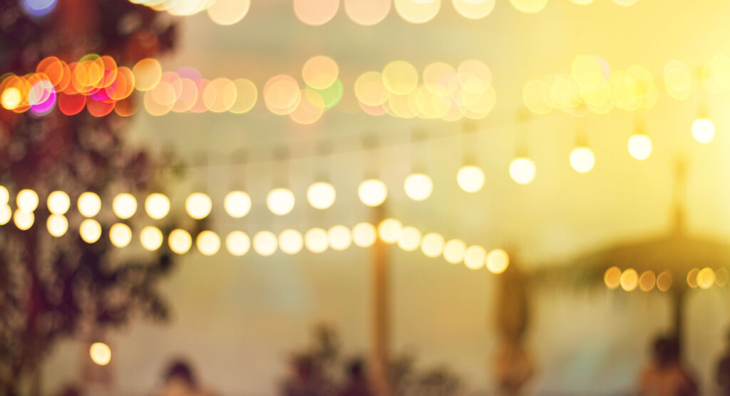 Verschwommene Lichterketten in sommerlicher Umgebung im Abendlicht.