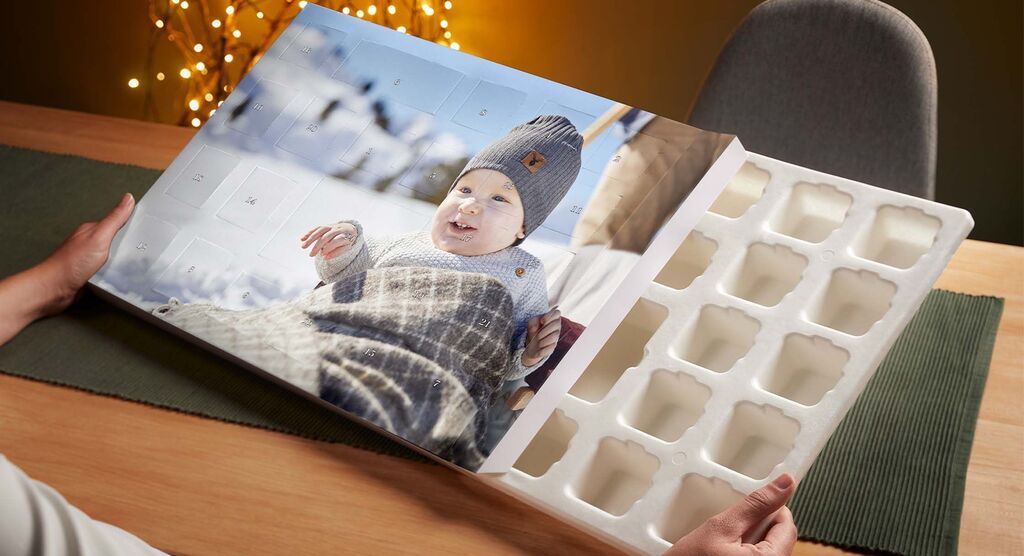 Ein geöffneter CEWE Fotokalender auf einem Tisch, mit einem schönen Bild von einem Kind in einem grauen Pullover.