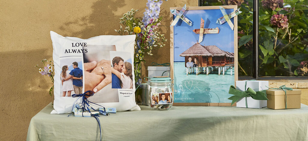 Ein dekorierter Tisch mit personalisierten Geschenken, darunter ein Kissen mit Fotos und eine Collage aus Erinnerungen. Es vermittelt Freude und persönliche Erinnerungen.