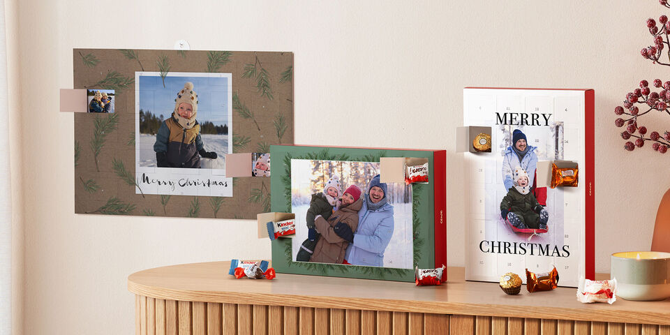 Drei Adventskalender von CEWE in Formate und Familienfotos auf einer weihnachtlichen geschmückten Kommode