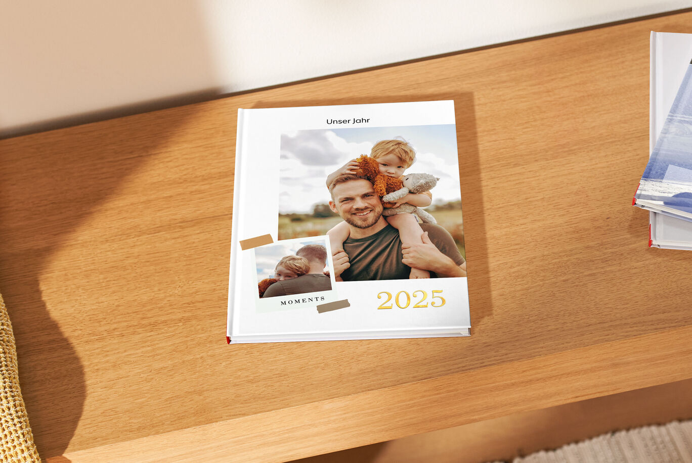 Ein CEWE FOTOBUCH liegt auf einem Holzregal. Das Cover zeigt eine liebevolle Umarmung und das Jahr 2024