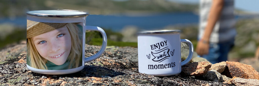 Zwei Tassen auf einem Stein beim Ausblick auf die Natur, eine Tasse zeigt ein persönliches Motiv. Perfekt für unvergessliche Momente.