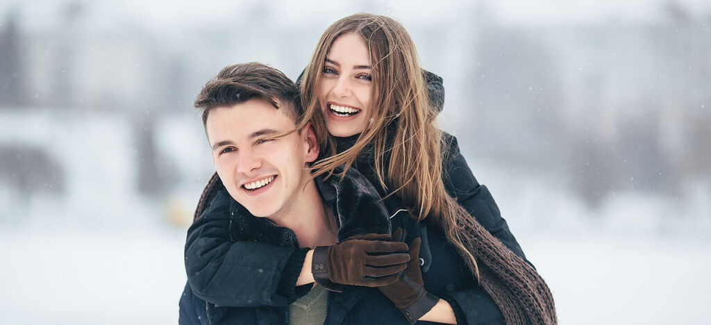 Ein Paar umarmt sich lächelnd im Schnee.
