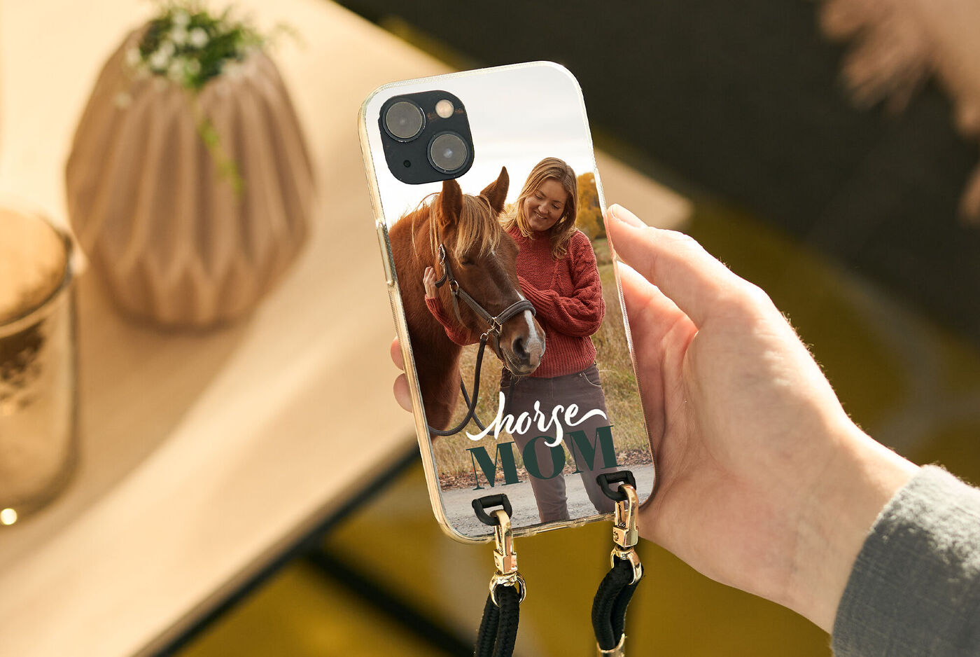 Eine Hand hält ein Handy mit einem personalisierten Cover, das ein Pferd zeigt.
