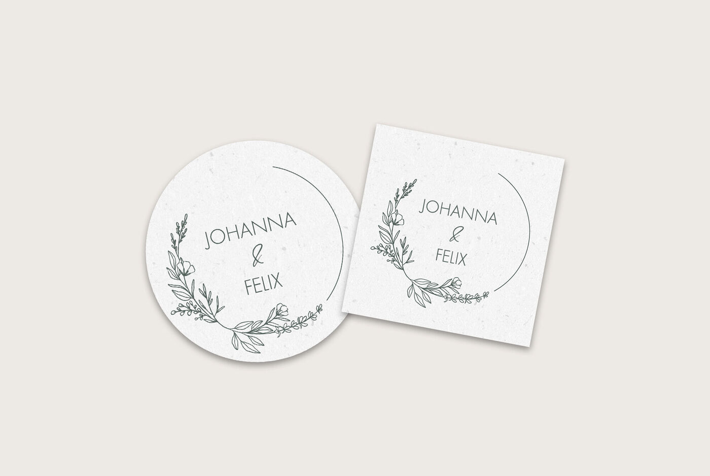 Ein Set mit zwei eleganten Einladungskarten, eine ovale und eine quadratische, mit den Namen Johanna und Felix in einer schönen Schrift umrahmt von zarten, floralen Motiven in Schwarz.