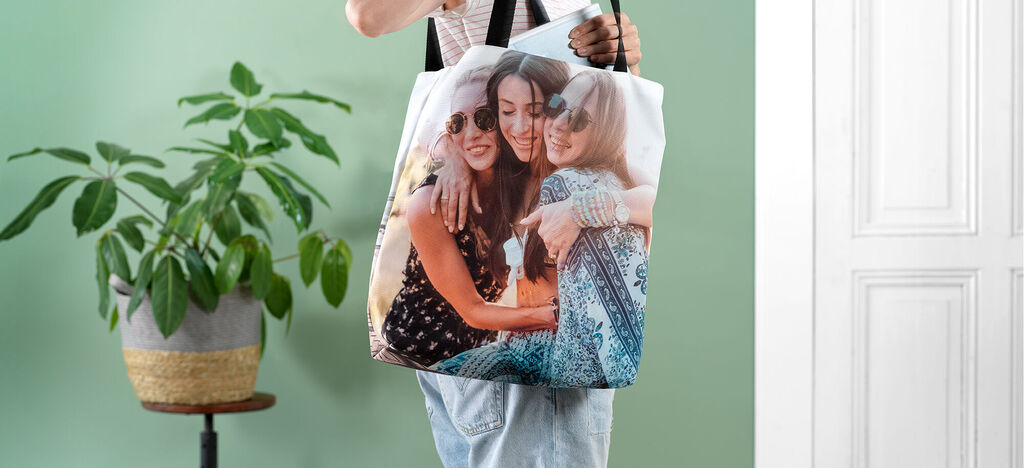 Eine Person hält eine Tasche mit einem Fotodruck von Freunden. Die Farben sind lebendig und die Atmosphäre ist freundlich.