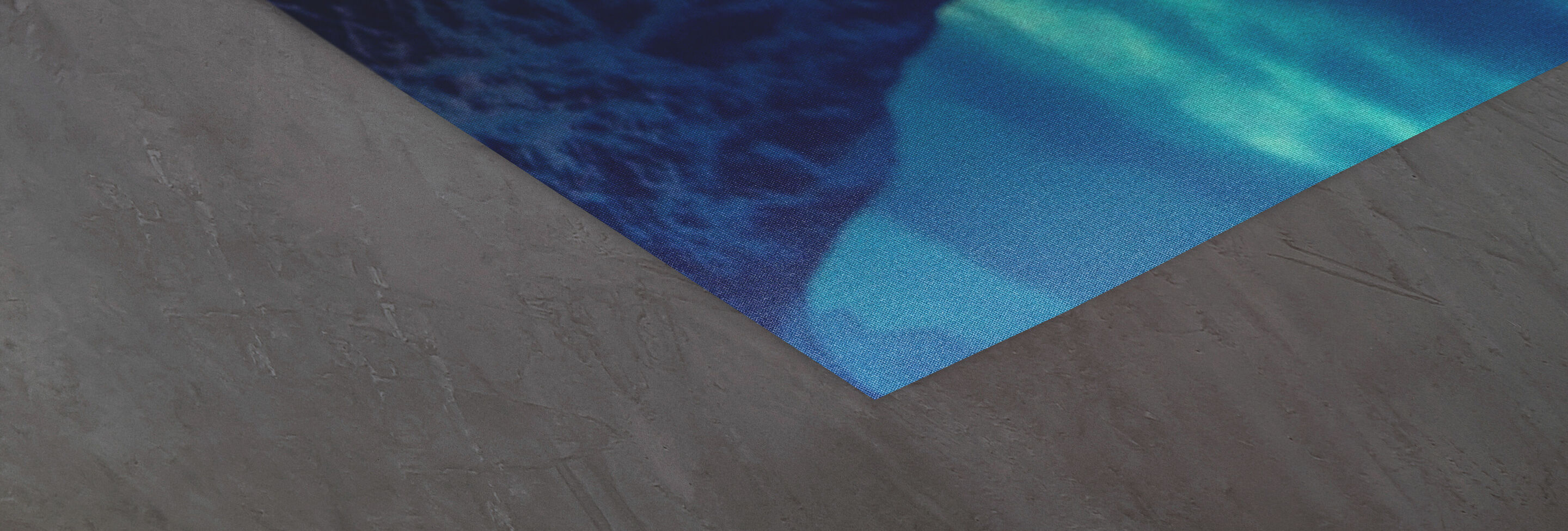 Kante eines Designs mit blauen und grünen Wellenmustern auf einem grau strukturierten Untergrund