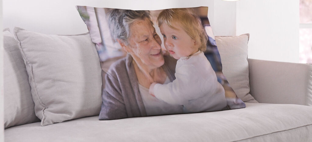 Kissen mit einem liebevollen Familienfoto, auf einem hellen Sofa platziert