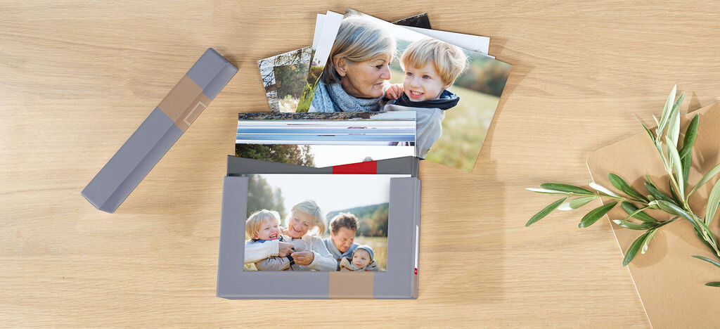 Ein Stapel von Fotos auf einem Tisch, darunter ein schön gestaltetes Fotobuch mit Familienbildern