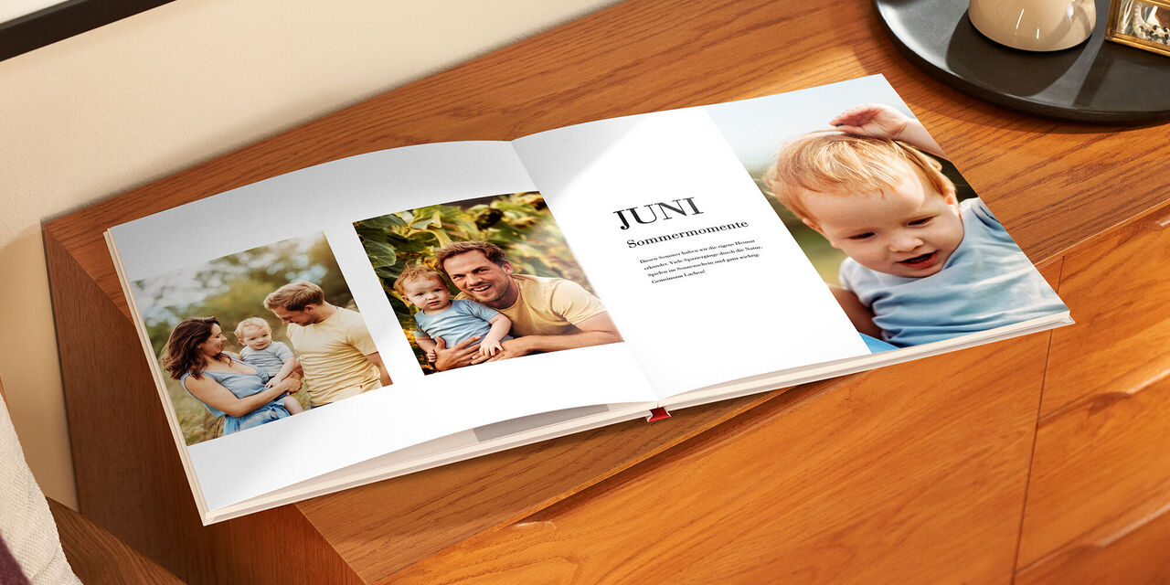 Ein offenes Fotobuch mit Bildern einer Familie im Freien. Im Vordergrund sind liebevolle Momente zu sehen. Der Monat Juni ist auf einer Seite abgebildet.