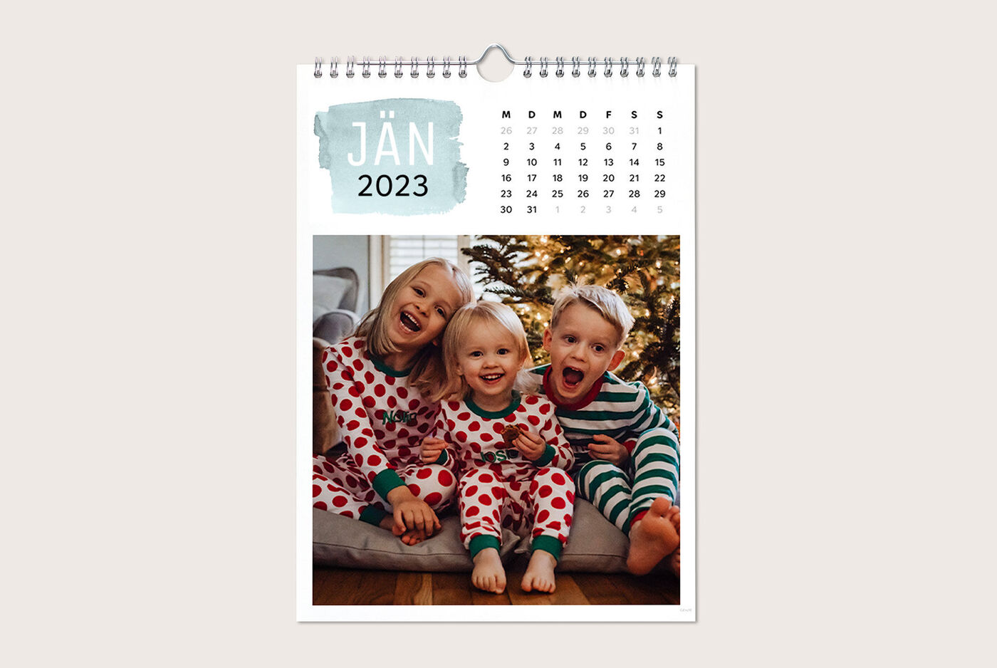Drei Kinder in Schlafanzügen auf einer Couch vor einem Weihnachtsbaum, Januar 2023, CEWE Fotokalender