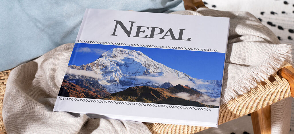 Ein offenes CEWE FOTOBUCH mit dem Titel Nepal, abgebildet auf einem Tisch.