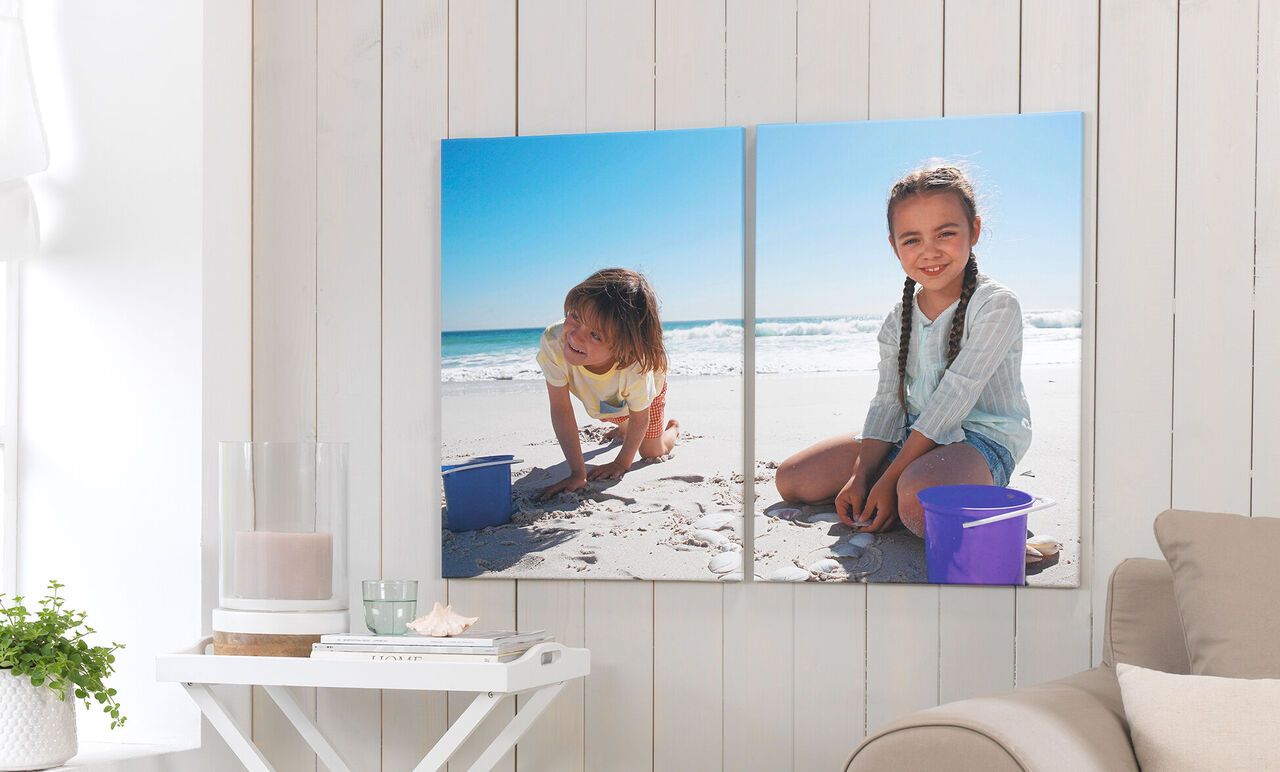 Zwei Kinder spielen am Strand mit Sand und Eimern
