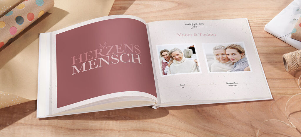 Ein geöffnetes CEWE FOTOBUCH mit liebevollen Erinnerungen und persönlichen Fotos. Auf einer Seite ist der Text "Herzensmensch" zu sehen.