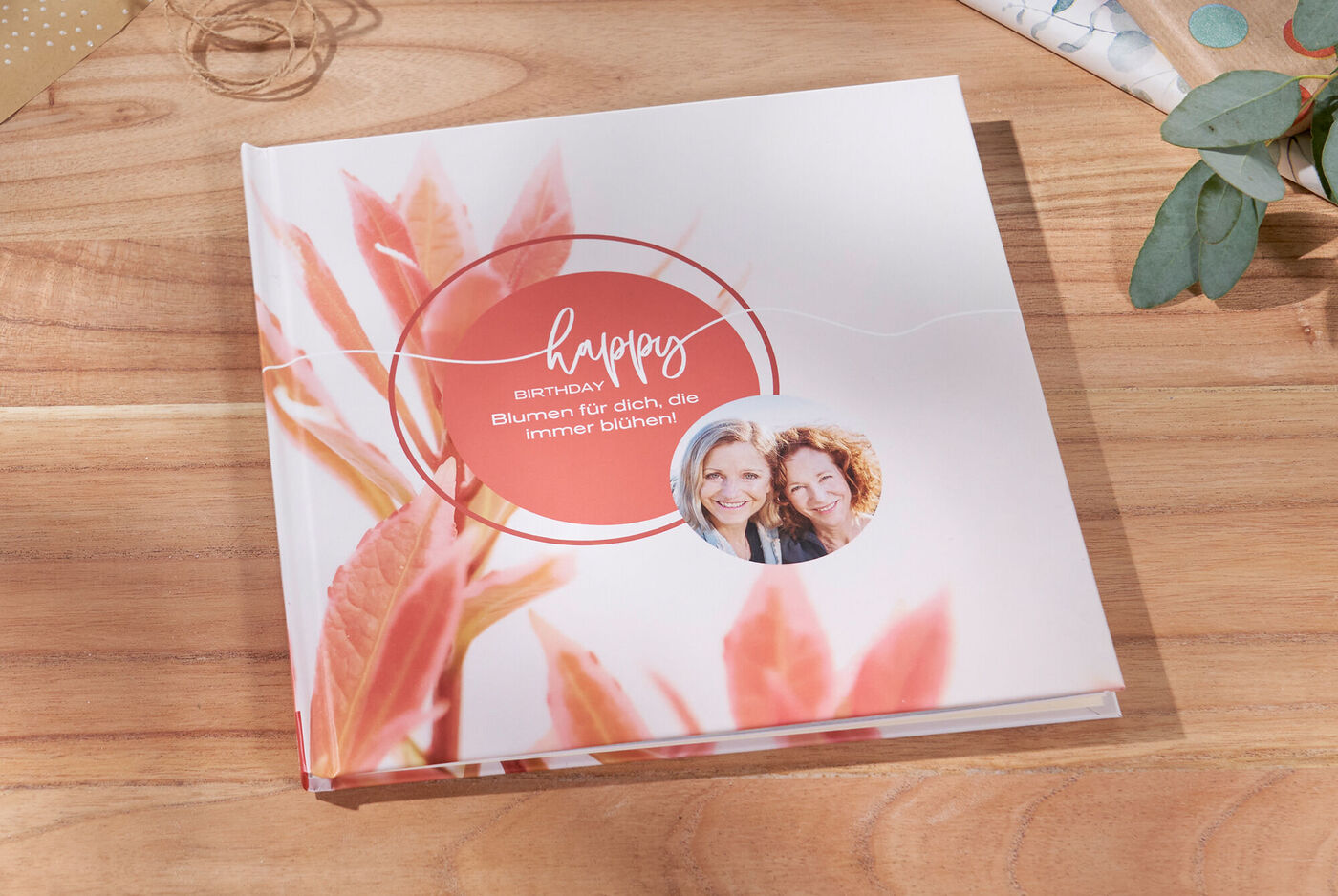 Ein CEWE Fotobuch mit floralem Cover und dem Schriftzug 'happy Birthday'.