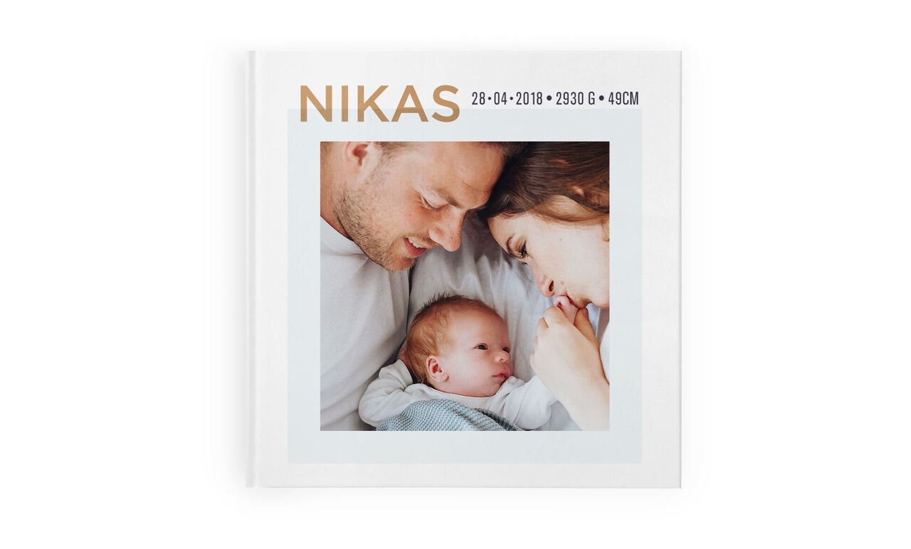 Ein glückliches Elternpaar schaut liebevoll auf ihr Baby in einem CEWE FOTOBUCH.