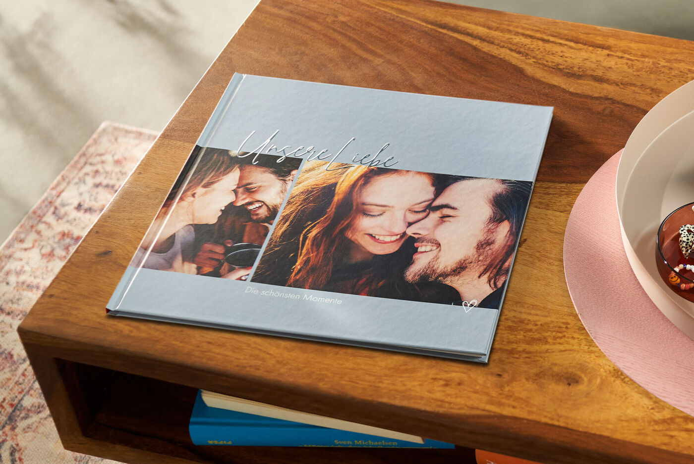 CEWE FOTOBUCH mit persönlichen Fotos liegt auf einem Tisch