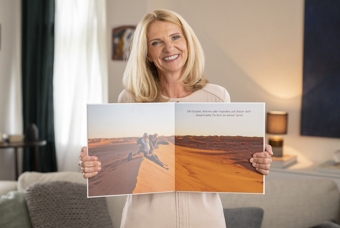 Eine Person hält ein aufgeschlagenes CEWE FOTOBUCH mit Erinnerungen in einer warmen Umgebung