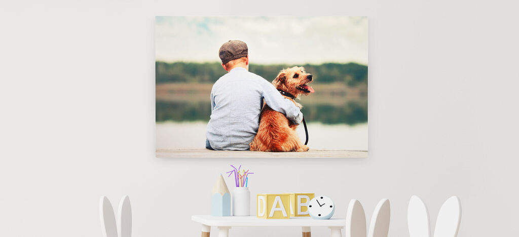 Ein Junge sitzt mit einem Hund am Ufer und schaut auf einen ruhigen See. Ihr Moment der Verbundenheit strahlt Freude und Liebe aus.
