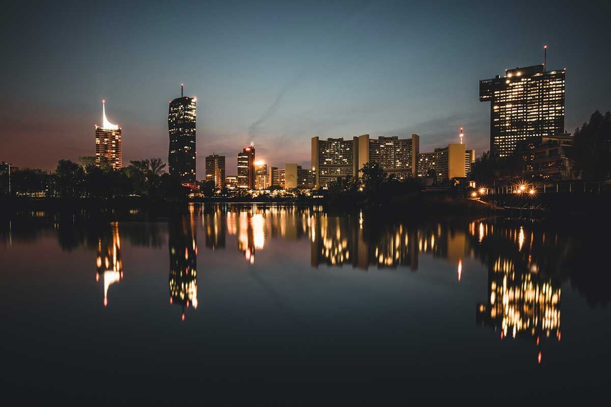 Beleuchtete Skyline von Wien bei Nacht mit Reflexionen im Wasser