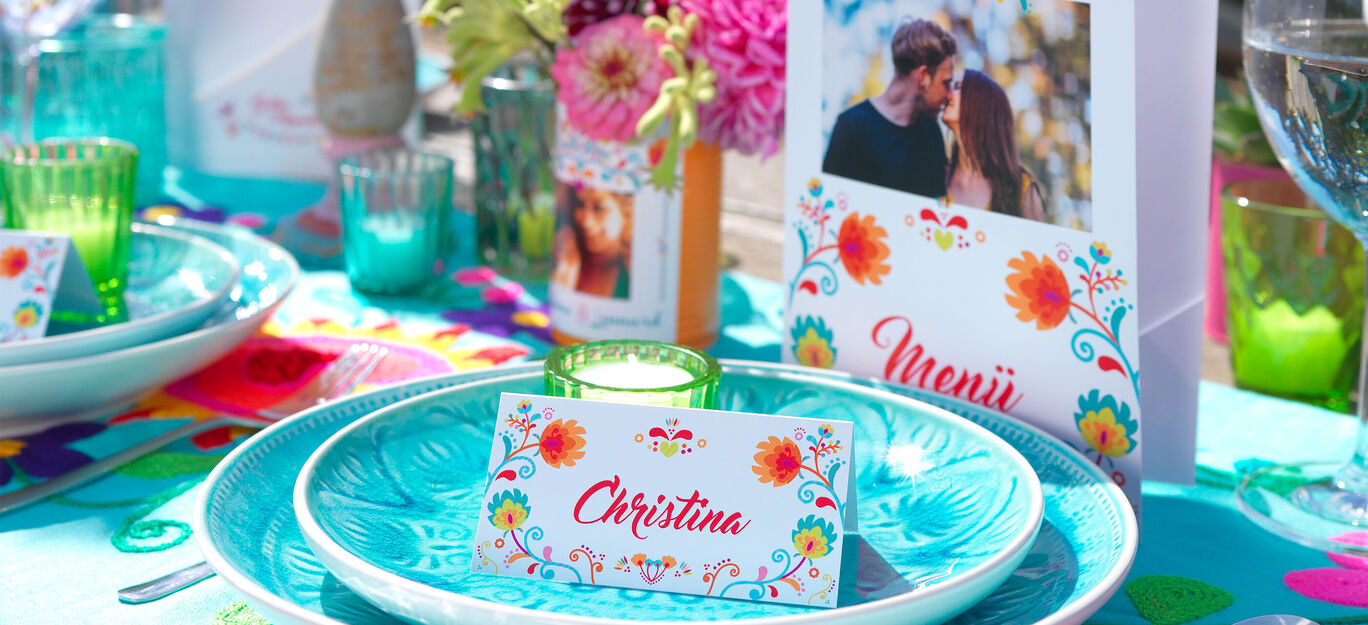 Ein liebevoll gestalteter Tisch mit blauen Tellern, bunten Blumen und Platzkarten mit dem Namen „Christina“.