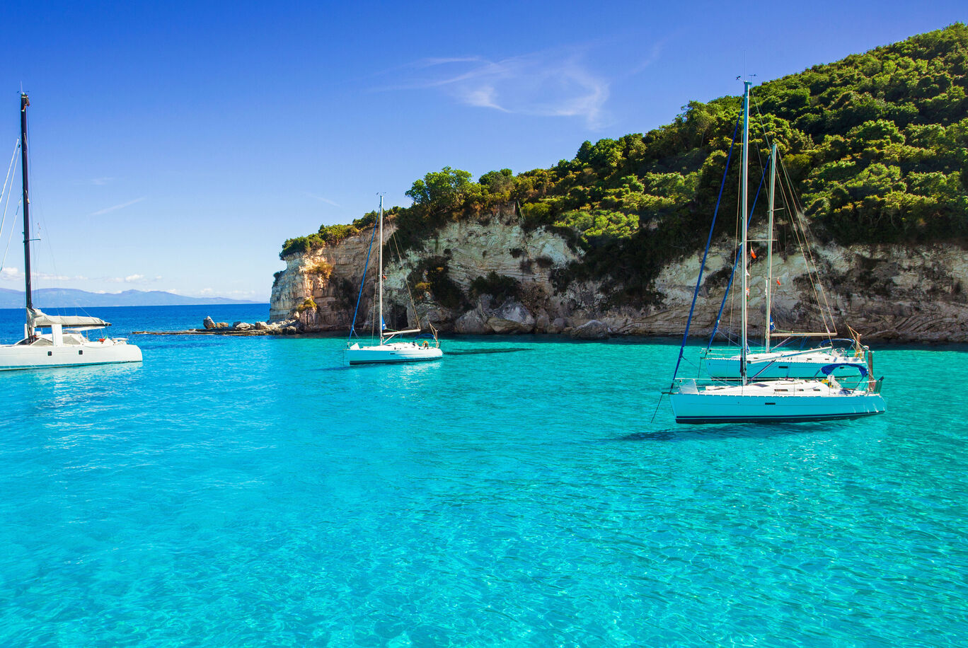 Drei Segelboote im klaren, blauen Wasser eines Urlaubsparadieses.