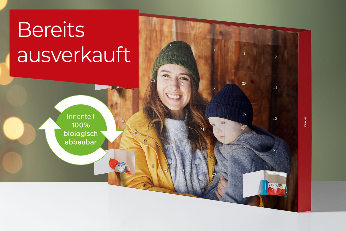 Ein attraktiver Adventskalender mit einem roten Cover. Der CEWE Kalender hat eine grüne, wiederverwertbare Box und zeigt eine herzliche Szene zwischen zwei Menschen. Der Text auf dem Cover sagt "Bereits ausverkauft".