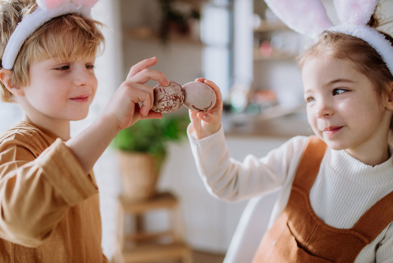 Zwei Kinder mit Hasenohren stoßen mit Macarons zusammen