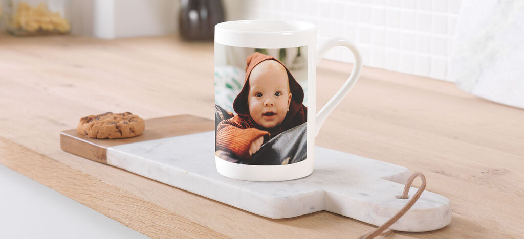 Tasse auf einem Holzbrett mit einem Keks daneben, umgeben von einer hellen Küche