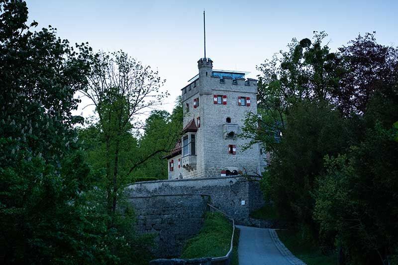 Historisches Schloss umgeben von Bäumen und grüner Natur, erstrahlt im sanften Abendlicht