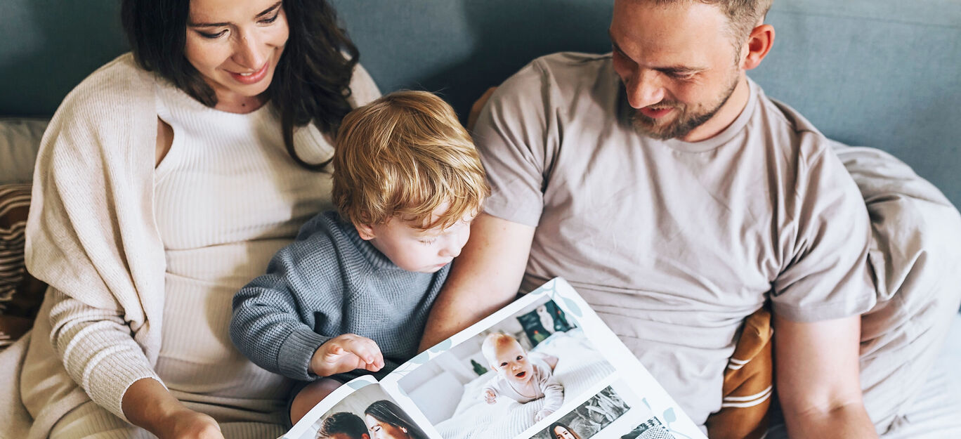 Eine Familie betrachtet gemeinsam ein Fotobuch mit schönen Erinnerungen.