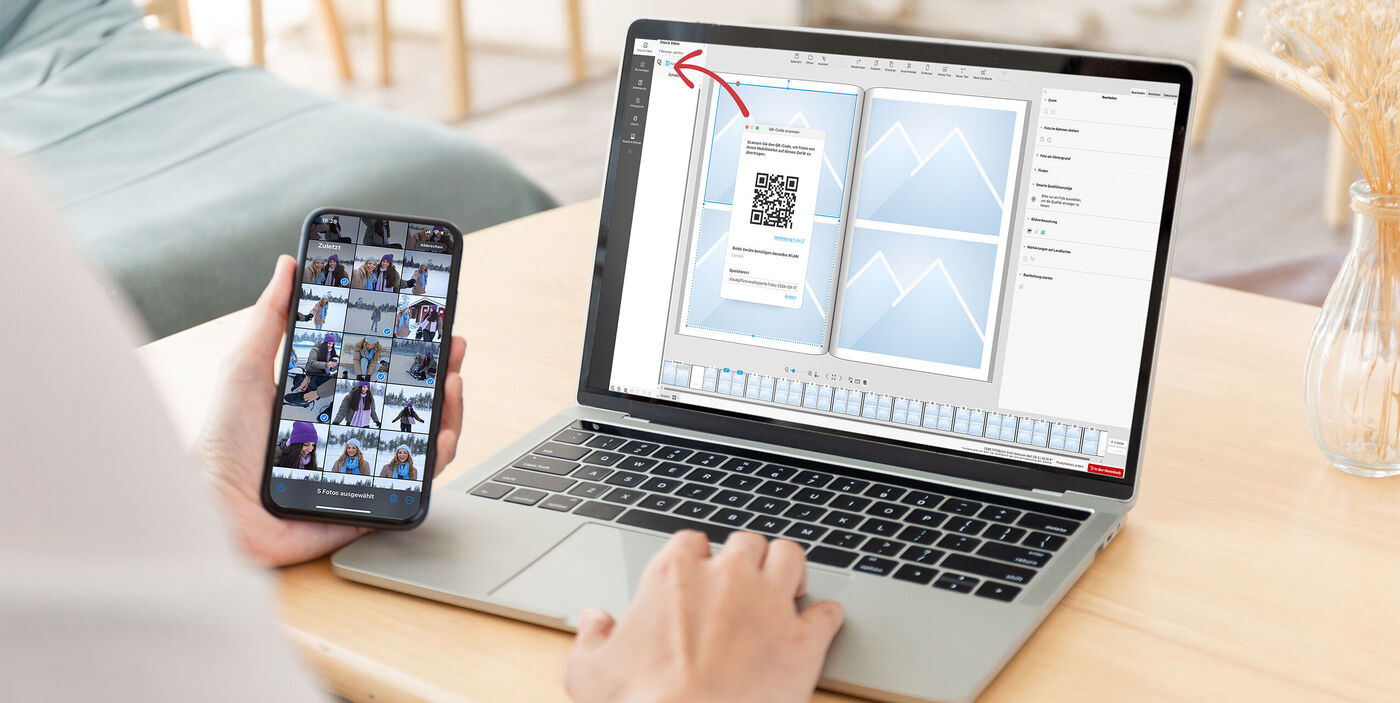 Aufgeklappter Laptop mit geöffneter CEWE Fotowelt Software. QR-Code für Smartphone Bilder Übertragung wird abgebildet.