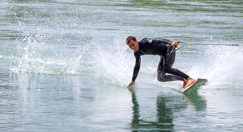 Ein Surfer gleitet über das Wasser und hinterlässt Spritzer.