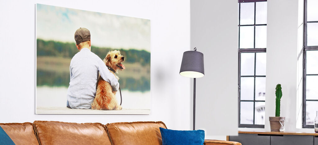 Ein Kind mit einer Mütze umarmt seinen Hund auf einem Wandbild. Beide schauen nach draußen. Der Hund sieht glücklich aus.