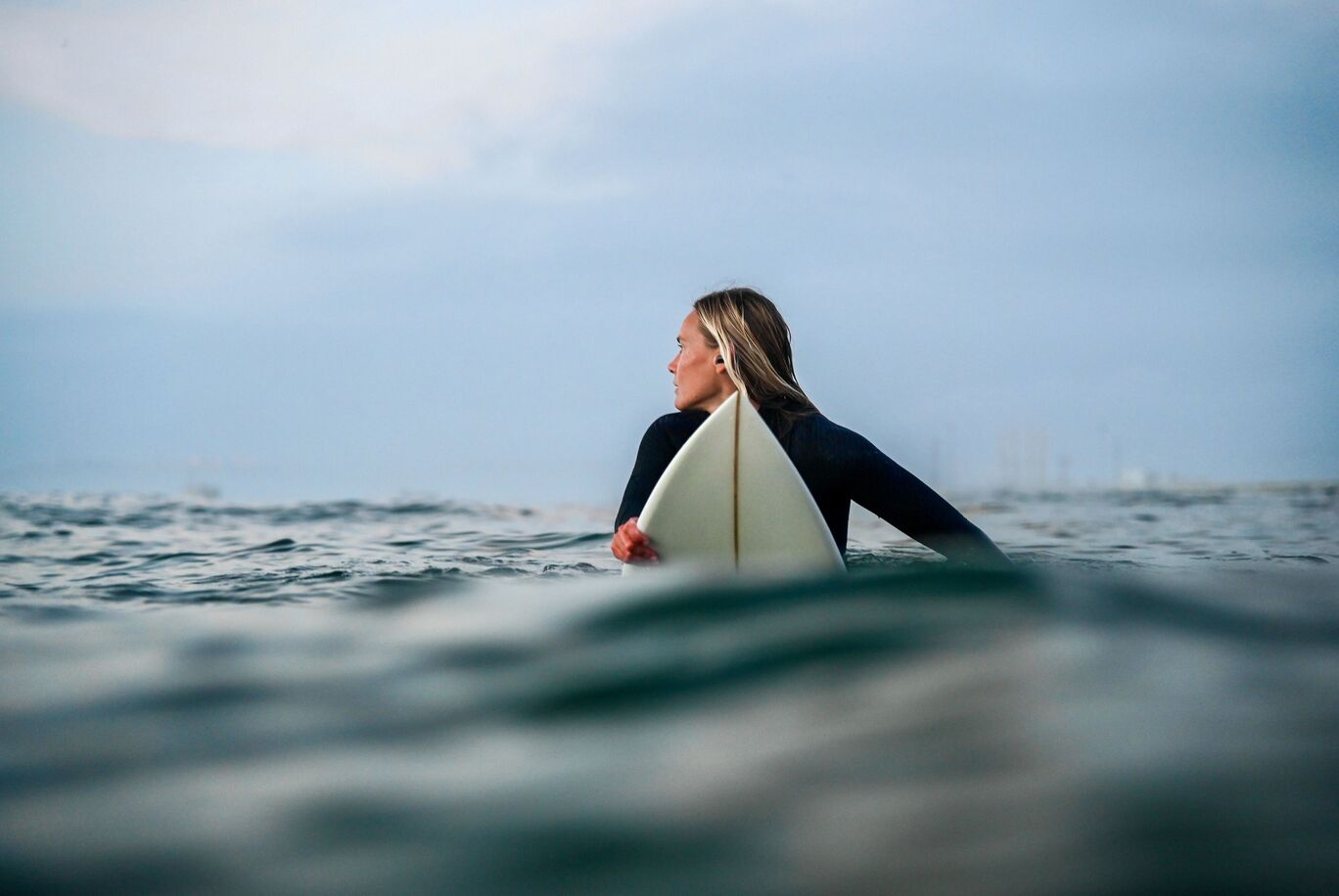 Person im Wasser mit Surfbrett, bereit zum Wellenreiten.