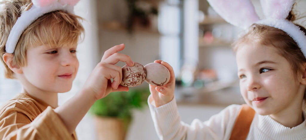 Zwei Kinder mit Hasenohren zeigen stolz ihre Schokoladenleckereien.