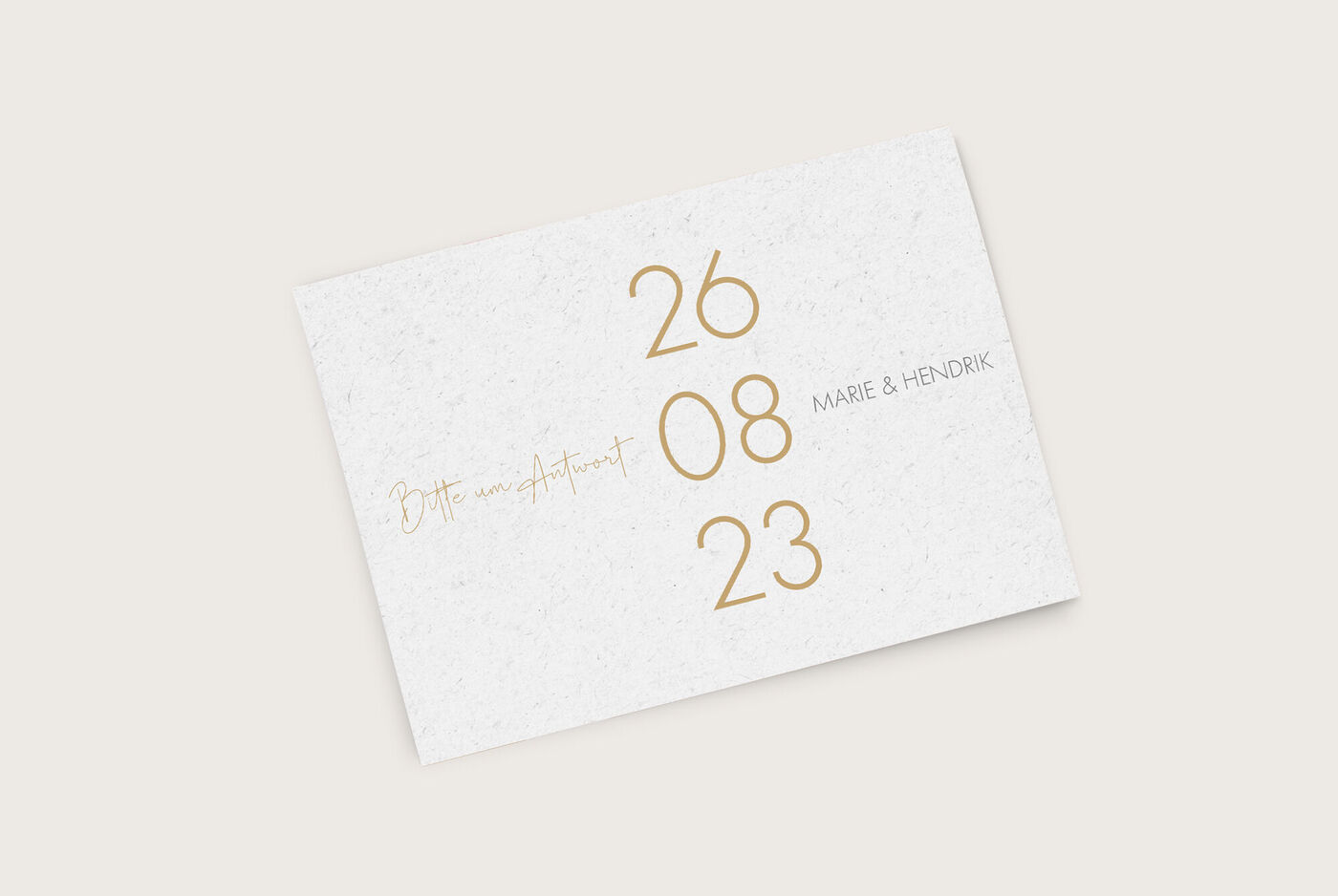 Ein elegantes Einladungskärtchen in weiß mit goldener Schrift, das den Text "Bitte um Antwort" sowie das Datum "26.08.23" und die Namen "Marie & Hendrik" präsentiert.