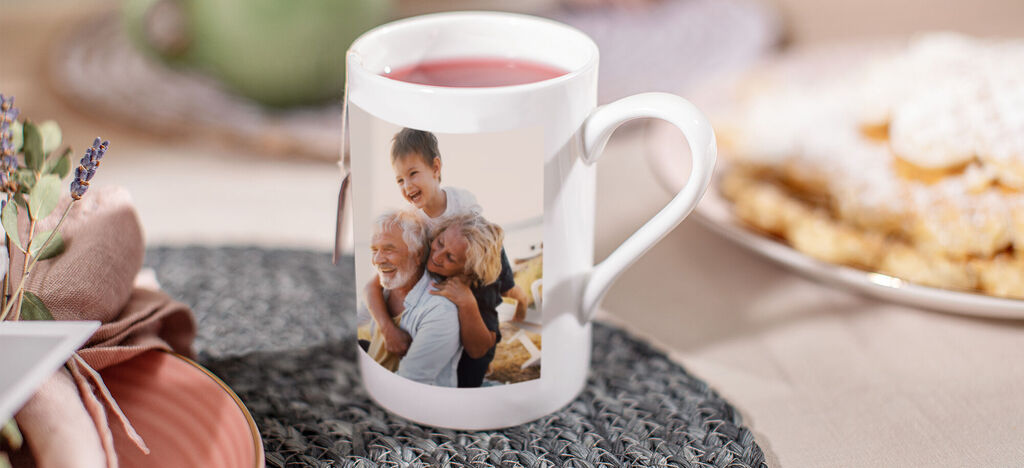 Tasse mit einem fröhlichen Bild von zwei älteren Menschen und einer Person, die sich umarmen