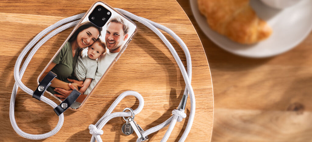 Ein Handy mit einem Fotomotiv auf einem Holztisch, umgeben von einer weißen Schnur, die das Handy hält