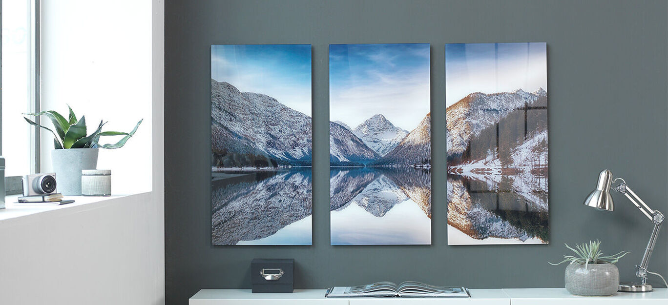 Drei schöne Bilder von verschneiten Bergen und einem klaren See, die an einer Wand hängen.