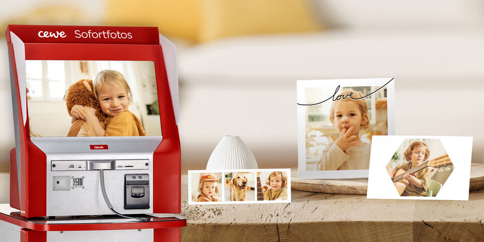 Ein CEWE Sofortfoto-Automat steht in einem gemütlichen Raum, umgeben von Fotos und einem dekorativen Element.