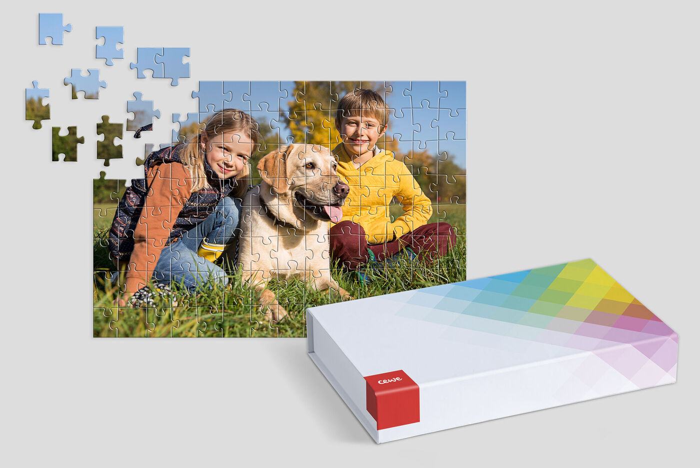 Ein Hund mit zwei Kindern sitzt auf einer Wiese, während Puzzle-Teile um sie herum liegen