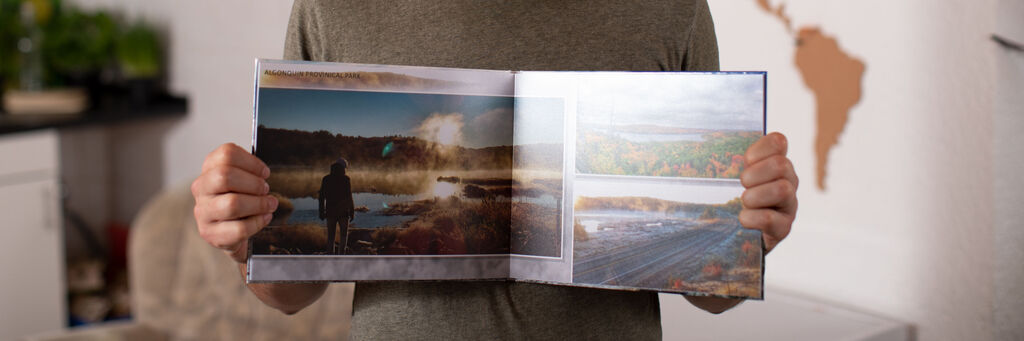 Eine Person hält ein geöffnetes Fotobuch mit Naturfotos.