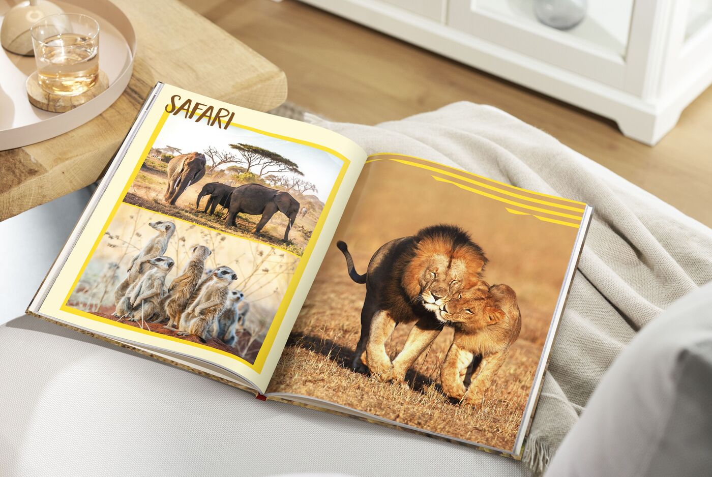 Ein offenes CEWE FOTOBUCH zeigt Safari-Motive mit Löwen und Elefanten.